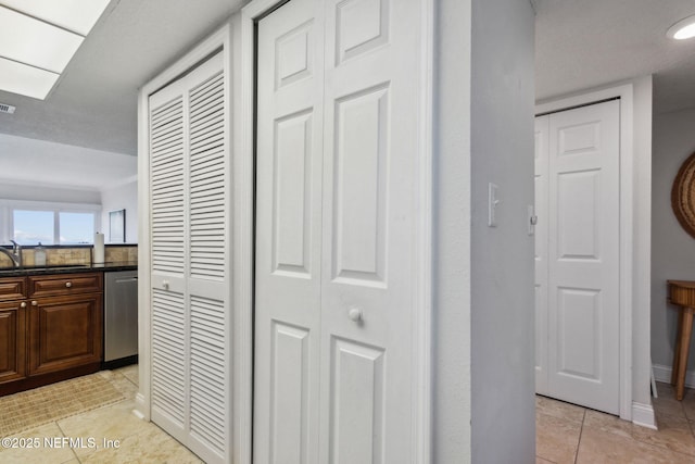 corridor featuring sink and light tile patterned flooring