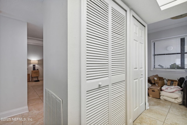 hall with light tile patterned flooring and ornamental molding