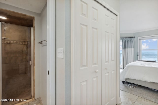 tiled bedroom with a closet, a water view, and ornamental molding