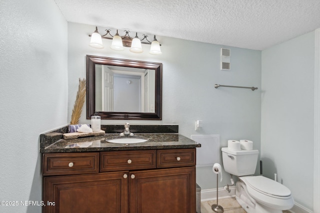 bathroom with tile patterned floors, vanity, toilet, and a textured ceiling