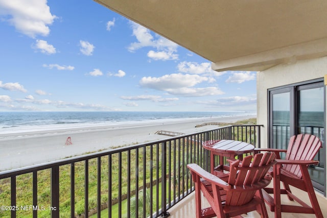 balcony featuring a view of the beach and a water view