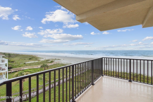 balcony with a water view and a view of the beach