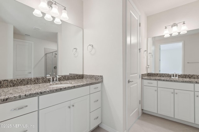 bathroom with a shower with door, vanity, and tile patterned flooring