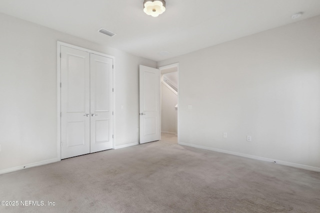 unfurnished bedroom featuring light colored carpet and a closet