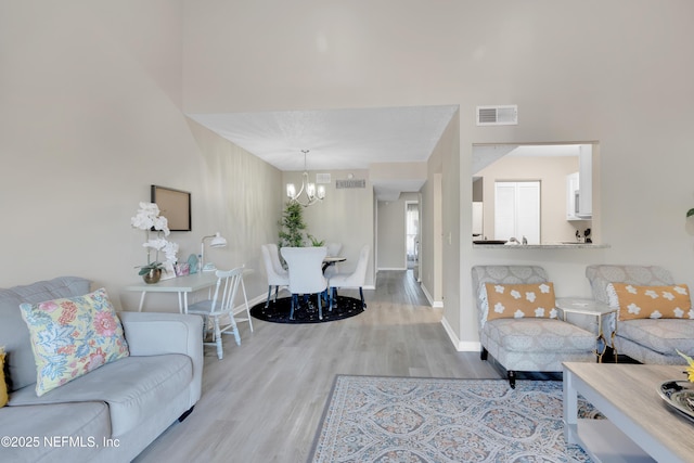 living room with light wood-type flooring and an inviting chandelier