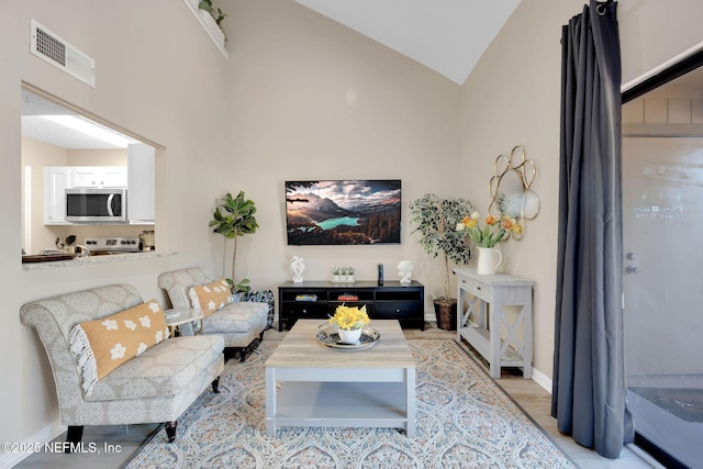 living room featuring light hardwood / wood-style flooring and high vaulted ceiling