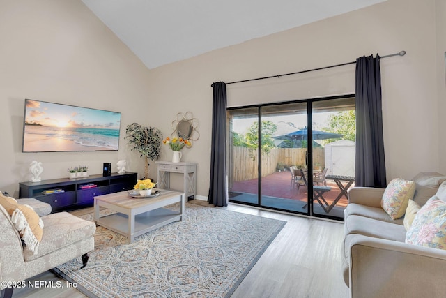 living room with light wood-type flooring and high vaulted ceiling