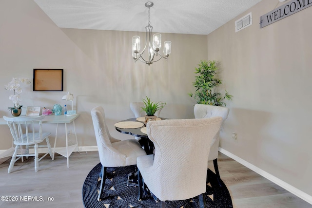 dining room with a chandelier, hardwood / wood-style floors, and a textured ceiling