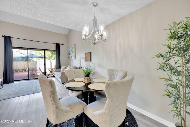 dining space featuring vaulted ceiling, a chandelier, a textured ceiling, and hardwood / wood-style flooring