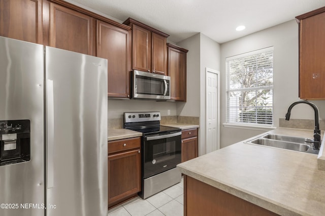 kitchen with appliances with stainless steel finishes, light tile patterned floors, and sink