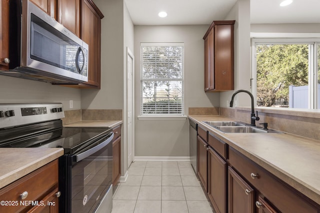 kitchen with a healthy amount of sunlight, sink, light tile patterned floors, and stainless steel appliances