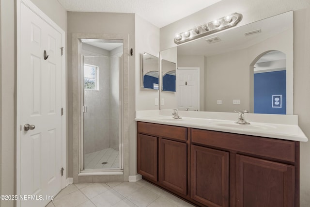 bathroom featuring tile patterned floors, a shower with door, vanity, and a textured ceiling