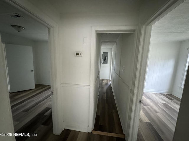 corridor with wood-type flooring and electric panel