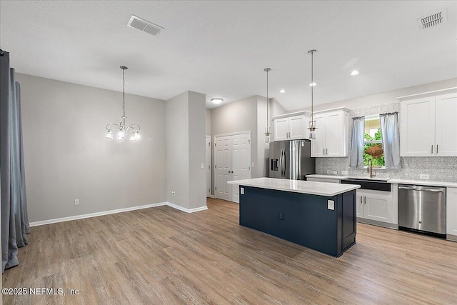 kitchen featuring pendant lighting, a center island, sink, appliances with stainless steel finishes, and white cabinetry