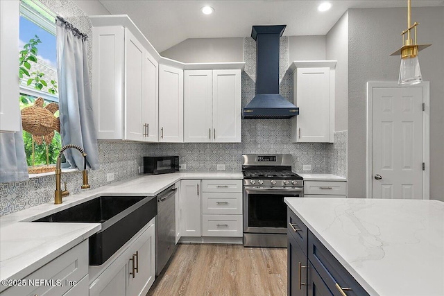 kitchen featuring white cabinets, light stone countertops, wall chimney exhaust hood, and stainless steel appliances