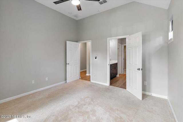 unfurnished bedroom featuring connected bathroom, ceiling fan, high vaulted ceiling, and light carpet