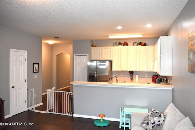 kitchen featuring kitchen peninsula, stainless steel fridge with ice dispenser, white cabinets, and a textured ceiling