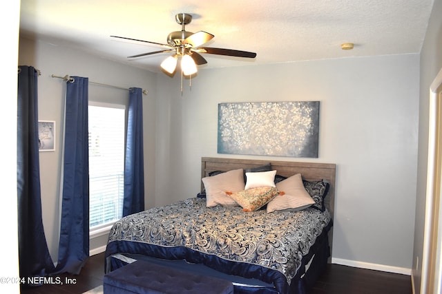 bedroom with ceiling fan, dark hardwood / wood-style flooring, and a textured ceiling