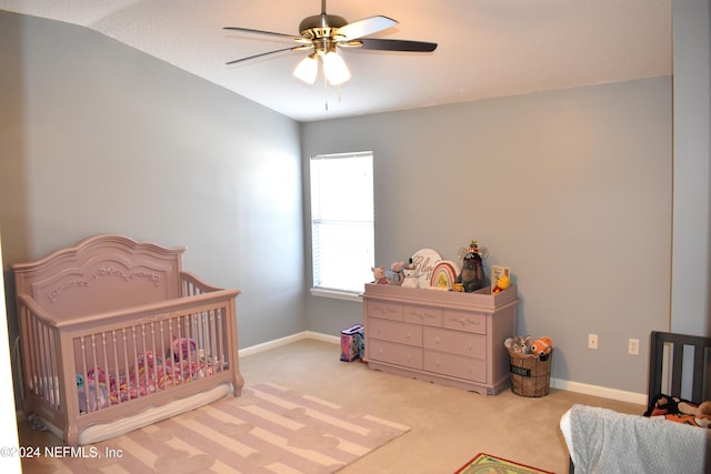 carpeted bedroom with ceiling fan, a crib, and lofted ceiling