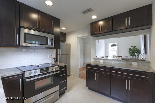 kitchen with light stone counters, decorative backsplash, dark brown cabinets, and appliances with stainless steel finishes