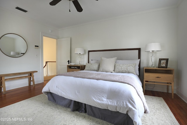 bedroom featuring dark hardwood / wood-style flooring, ornamental molding, and ceiling fan