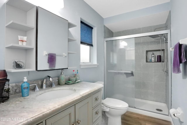 bathroom with wood-type flooring, vanity, toilet, and a shower with shower door