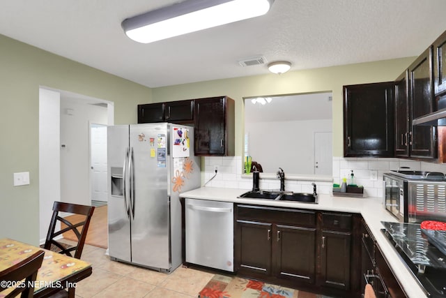 kitchen with decorative backsplash, appliances with stainless steel finishes, a textured ceiling, sink, and light tile patterned flooring