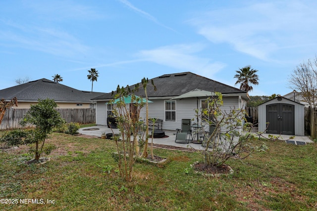 rear view of property featuring a lawn, a patio, and a shed