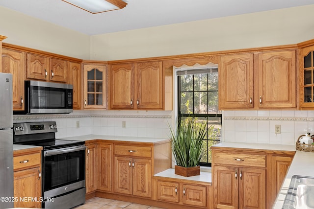 kitchen with appliances with stainless steel finishes, backsplash, and light tile patterned flooring