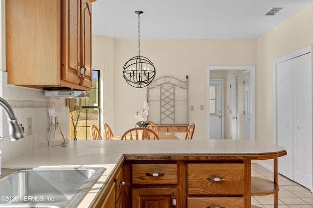 kitchen with sink, backsplash, kitchen peninsula, decorative light fixtures, and light tile patterned floors