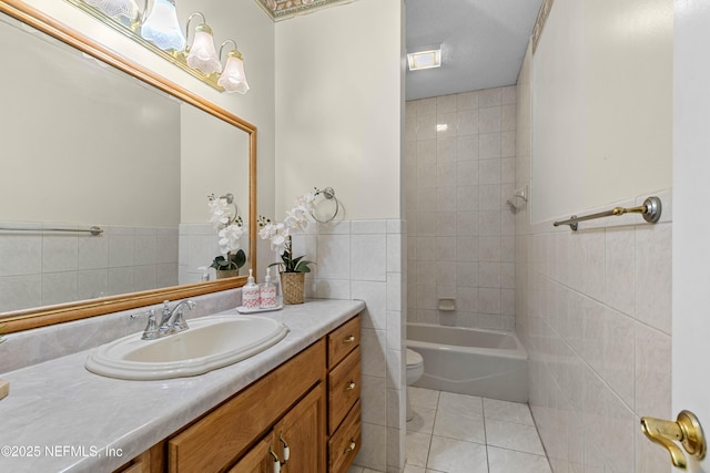 full bathroom featuring vanity, tile patterned flooring, tiled shower / bath combo, toilet, and tile walls