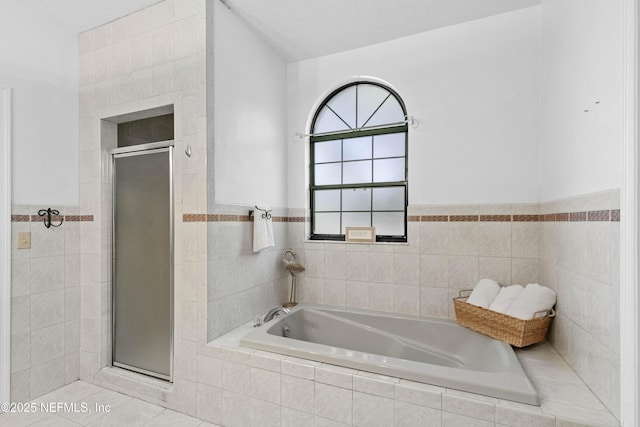 bathroom featuring tile patterned floors, a textured ceiling, separate shower and tub, and tile walls