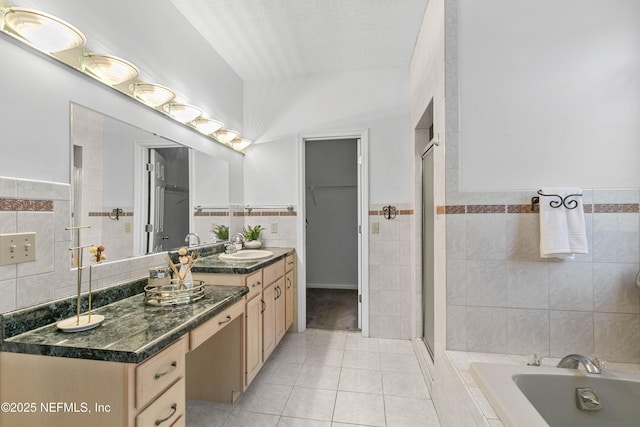 bathroom with vanity, a textured ceiling, tile walls, plus walk in shower, and tile patterned flooring