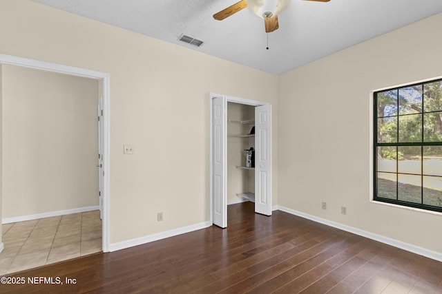 unfurnished bedroom with a textured ceiling, ceiling fan, a closet, and dark hardwood / wood-style floors