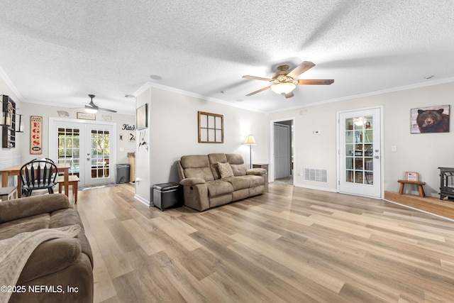 living room featuring a textured ceiling, ornamental molding, and french doors