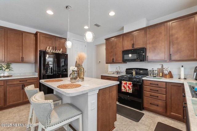 kitchen featuring a center island, decorative light fixtures, a breakfast bar, and black appliances