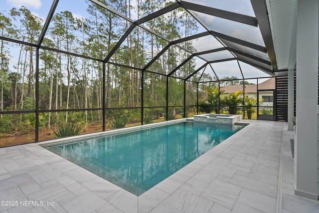 view of pool featuring glass enclosure, an in ground hot tub, and a patio