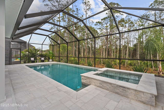 view of swimming pool with an in ground hot tub, glass enclosure, and a patio