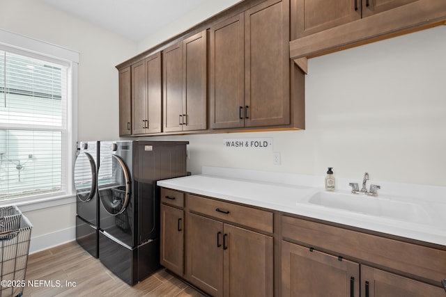 clothes washing area featuring plenty of natural light, cabinets, sink, and washing machine and clothes dryer