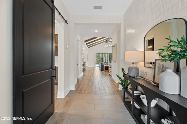 hallway featuring lofted ceiling with beams, a barn door, and an inviting chandelier