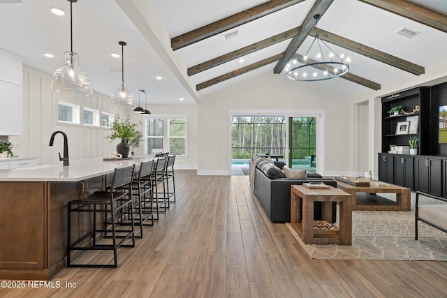 living room with an inviting chandelier, built in features, vaulted ceiling with beams, and sink