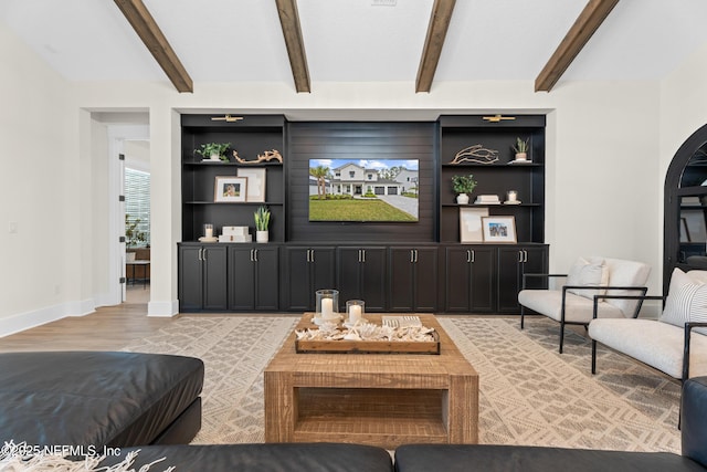 living room featuring built in shelves, light hardwood / wood-style flooring, and beam ceiling