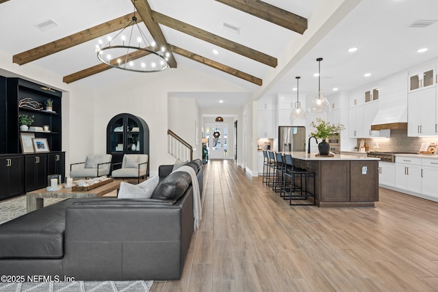 living room with high vaulted ceiling, light hardwood / wood-style flooring, beam ceiling, and a notable chandelier