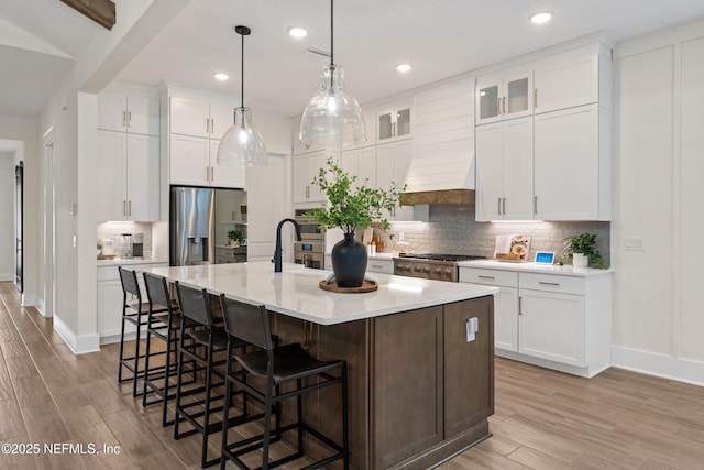 kitchen featuring a center island with sink, white cabinetry, light wood-type flooring, a kitchen breakfast bar, and stainless steel appliances