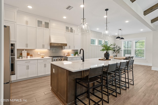 kitchen with decorative light fixtures, a breakfast bar, sink, a large island, and white cabinets