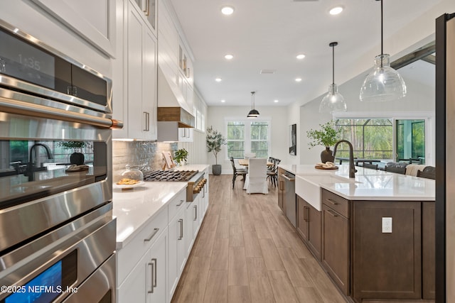 kitchen with sink, pendant lighting, white cabinets, and stainless steel appliances