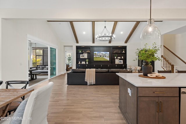 kitchen with vaulted ceiling with beams, light stone counters, hanging light fixtures, and built in shelves