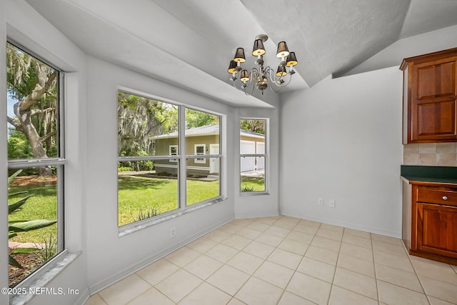 unfurnished dining area featuring a chandelier, vaulted ceiling, and plenty of natural light