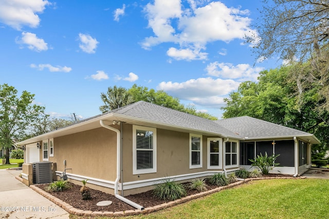 ranch-style home with central air condition unit, a sunroom, a front lawn, and a garage