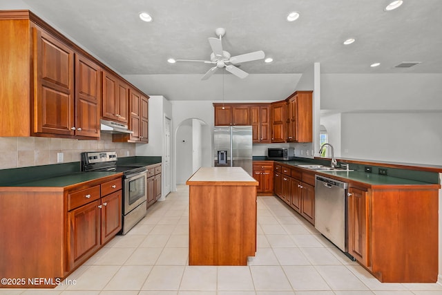 kitchen featuring appliances with stainless steel finishes, ceiling fan, sink, light tile patterned floors, and a center island